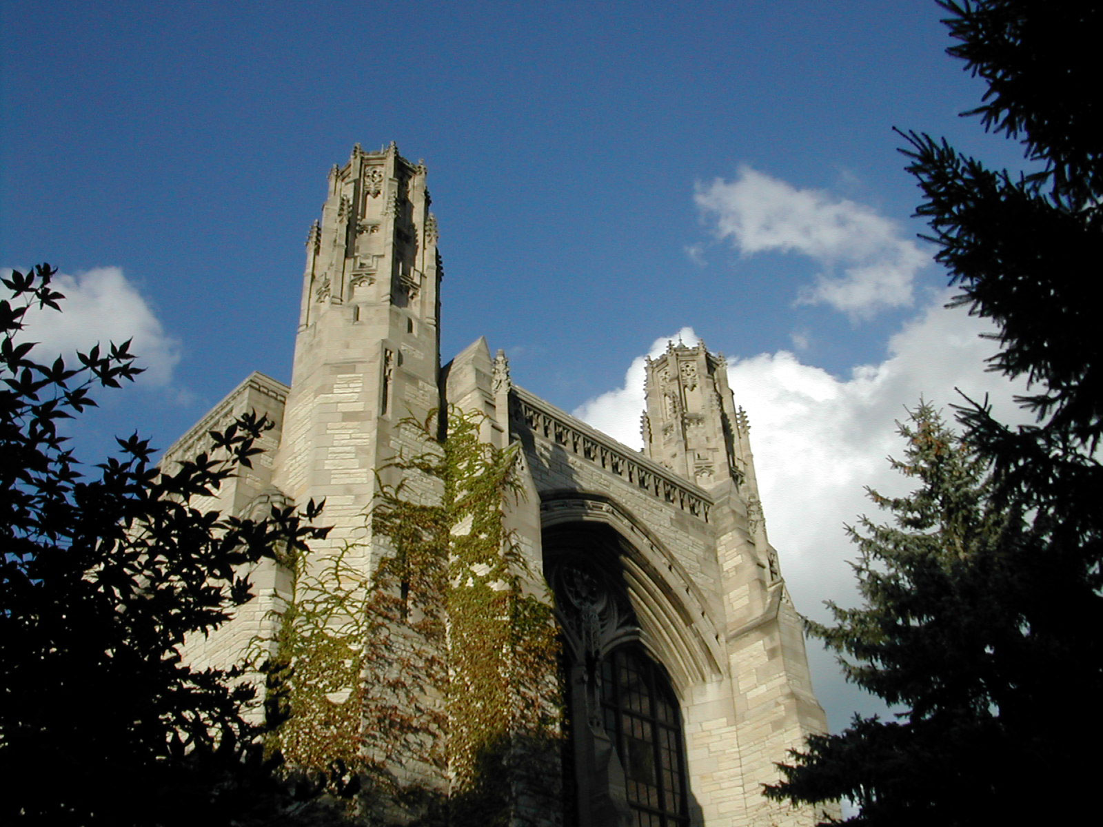 A photo from the ground looking up at the southeast corner of the Deering towers, with a blue sky behind. 